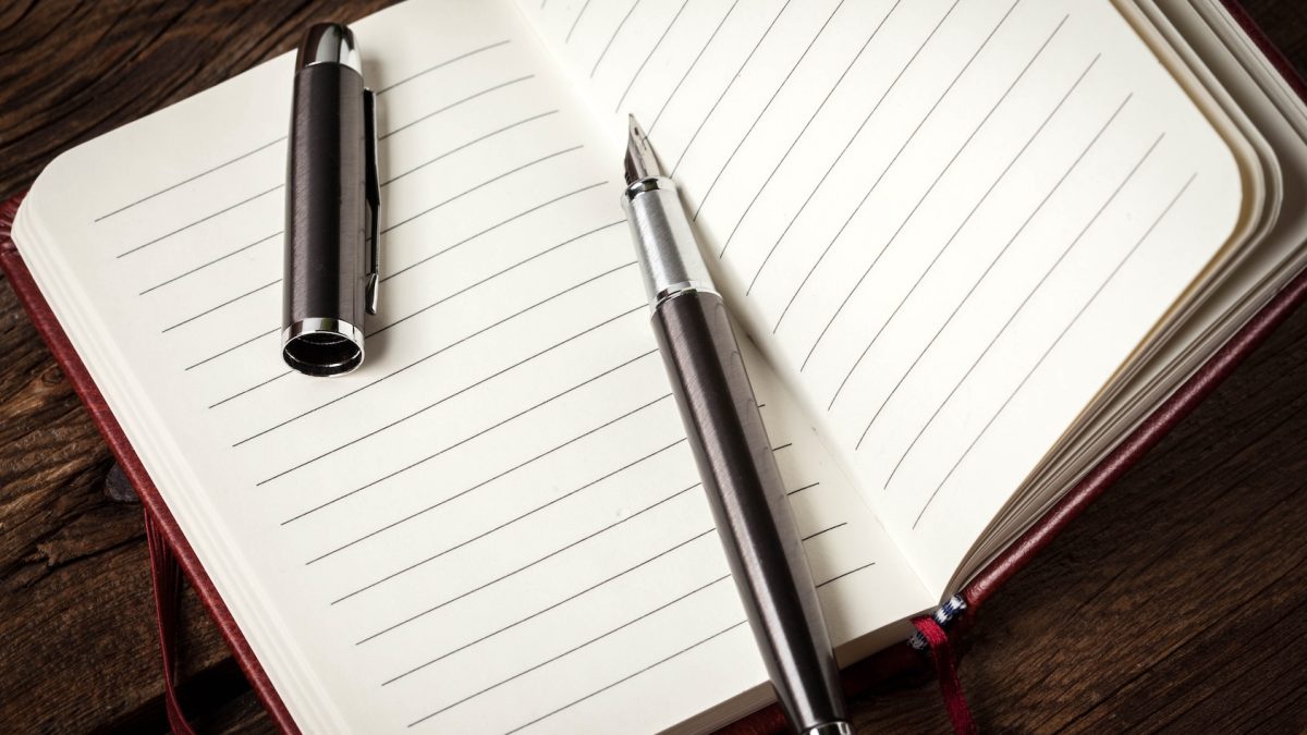 Caderno em branco e caneta de tinta.