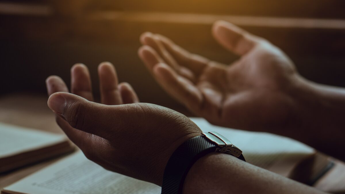 Mãos de um homem com a Bíblia orando