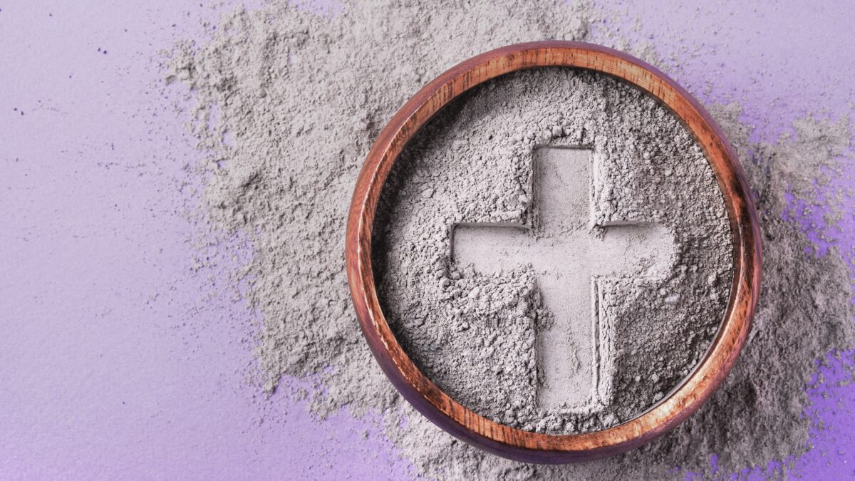 Cross imprint in gray ash on purple background. Ash Wednesday.