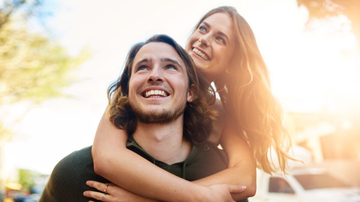 Piggyback, travel and happy couple in city together for relationship, bonding or tourism for weekend break. Smile, outdoor and people in urban town street for adventure, holiday or vacation in Miami.