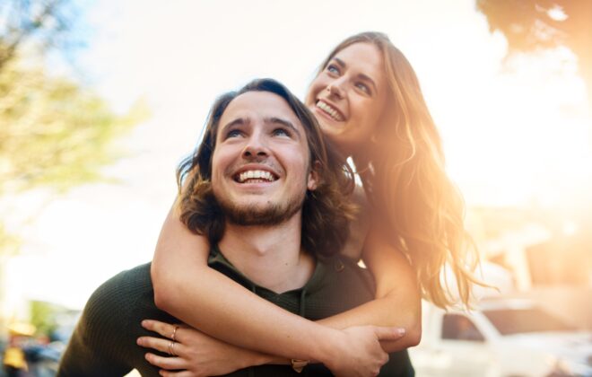 Piggyback, travel and happy couple in city together for relationship, bonding or tourism for weekend break. Smile, outdoor and people in urban town street for adventure, holiday or vacation in Miami.