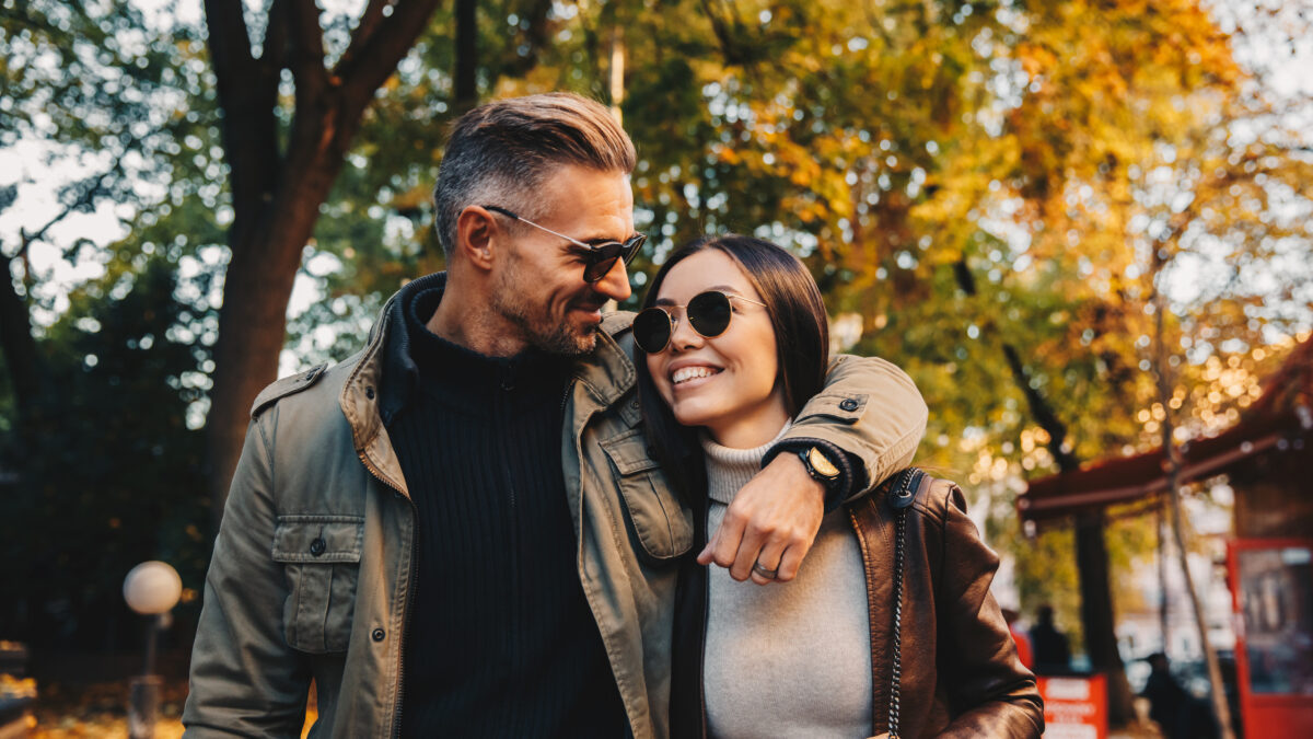 Autumn walk. Couple. Love. Man and woman in warm casual clothes are hugging and smiling while walking in the park