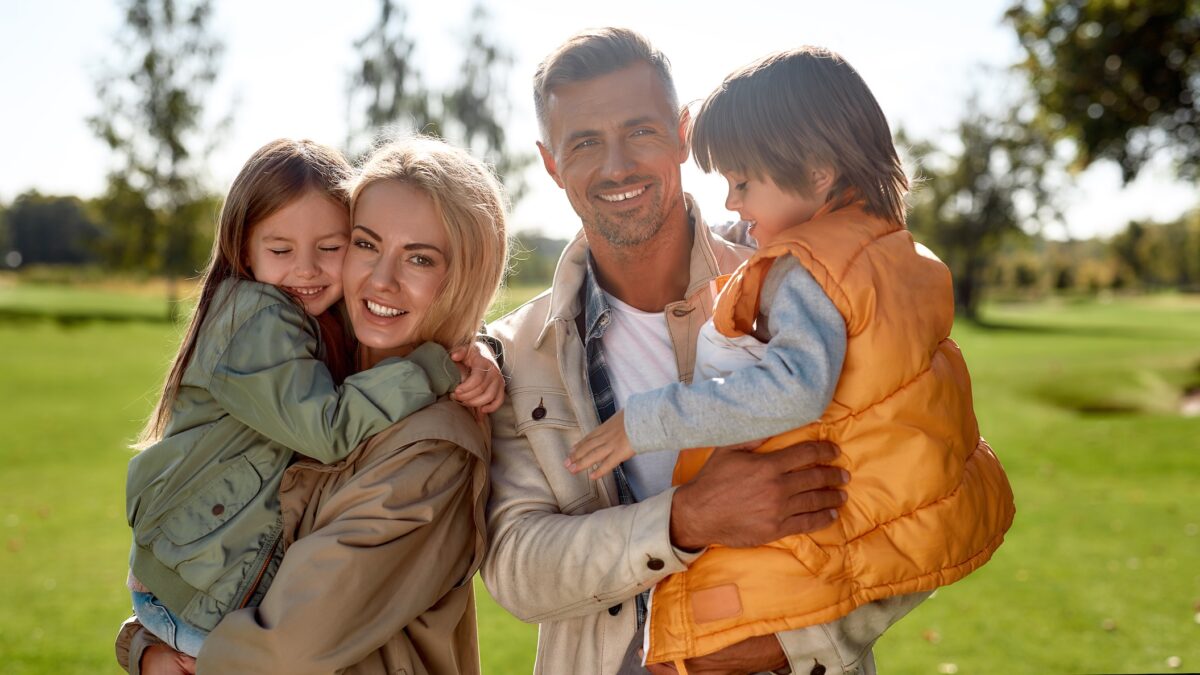 Daughter and son. Portrait of happy and beautiful family with children looking at camera with smile while standing in the park on a sunny day. Family concept. Nature