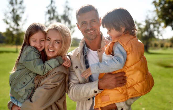 Daughter and son. Portrait of happy and beautiful family with children looking at camera with smile while standing in the park on a sunny day. Family concept. Nature