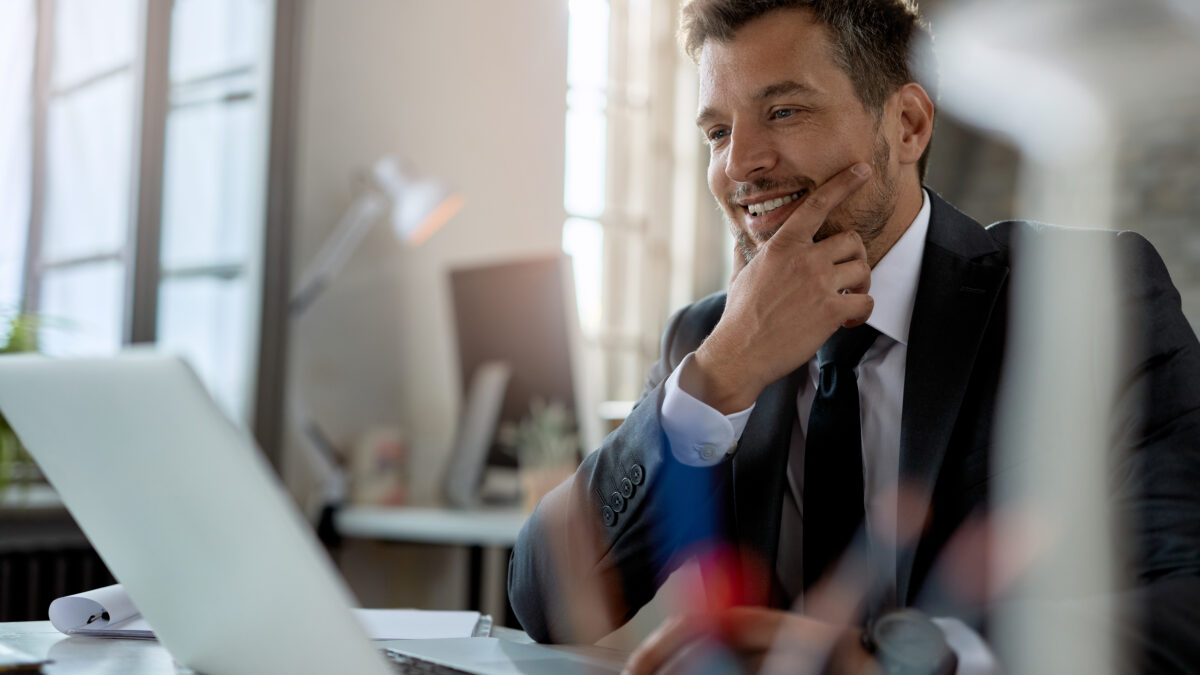 Smiling mid adult businessman using computer while working at office desk.
