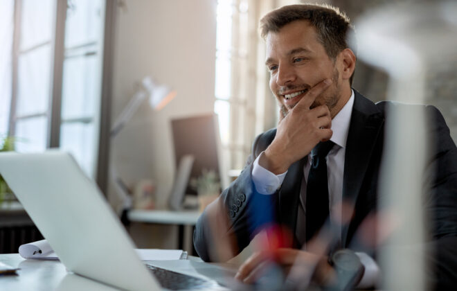 Smiling mid adult businessman using computer while working at office desk.